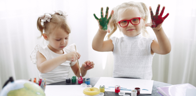 Two young girls engaging in a painting activity, showcasing creativity and skill development, which aligns with the benefits of occupational therapy for autism in fostering fine motor skills and self-expression
