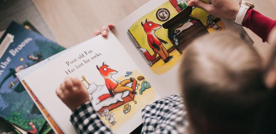 A parent reading a book to their child about speech delay vs. autism, concerned about their child's delayed speech or possible signs of autism.