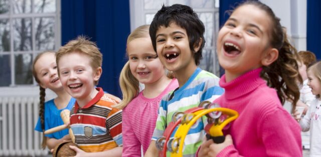 A diverse group of children laughing together in a classroom, representing inclusive learning and education for autism.