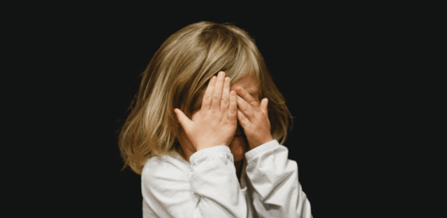 Why My Child Hates School — sad young child sitting alone, covering eyes with hands, showing stress and frustration.