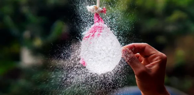 A hand popping a water balloon in midair, symbolizing breaking unconditional positive regard misconceptions and revealing the truth beneath.