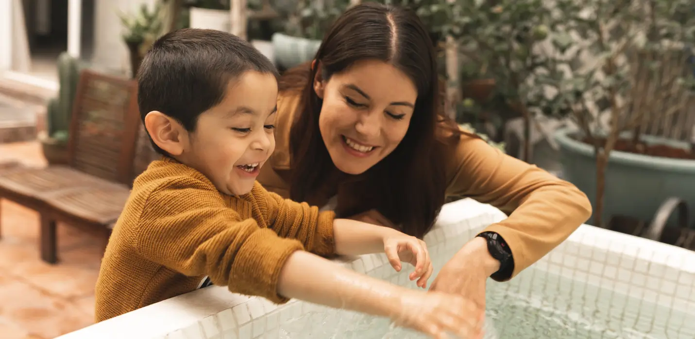 Mother laughing with her young son while playing with water outside — support for Ohio families after an autism diagnosis